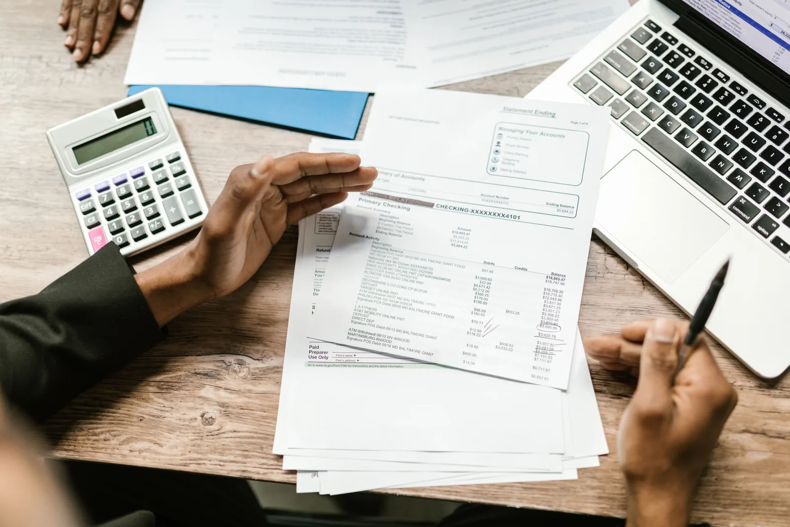 Hands holding financial documents with calculator and laptop on office desk, business analysis scene. Platform fees and payouts: what a membership community actually keeps